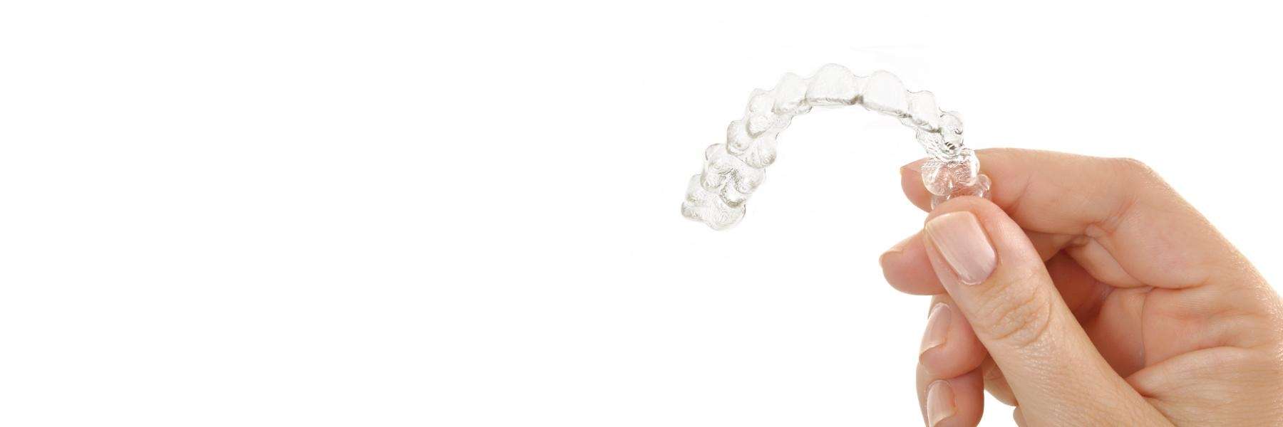 A hand holding invisalign braces. 