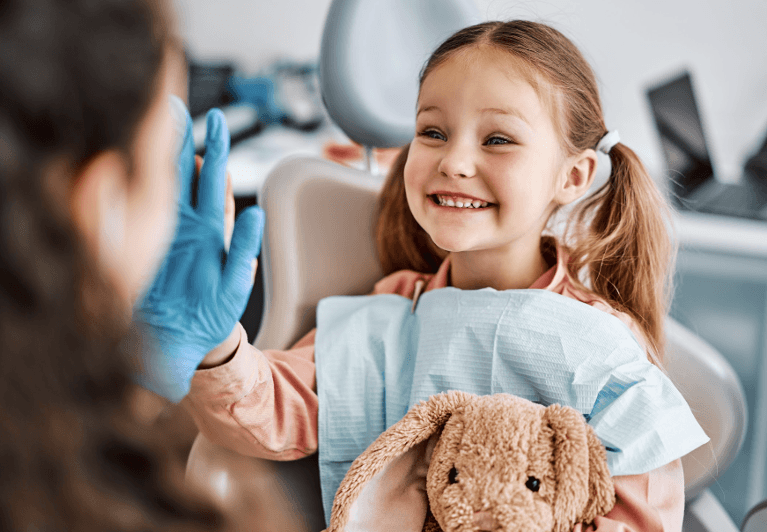 A small child giving her dentist a high five