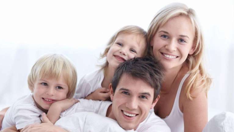 A happy family laying down and posing for a picture | dentist in Tamsworth
