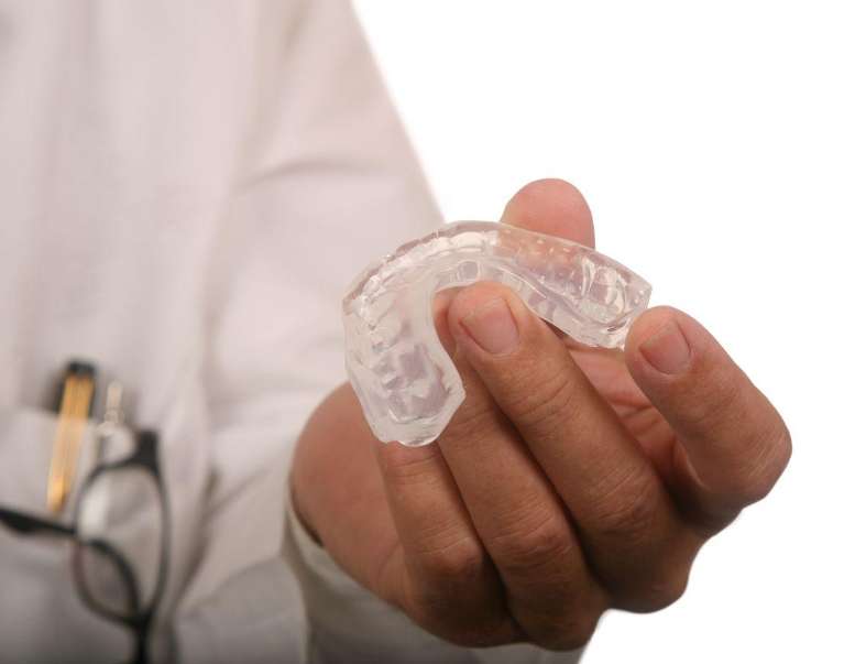 Close-up of hand displaying Invisalign-style clear braces
