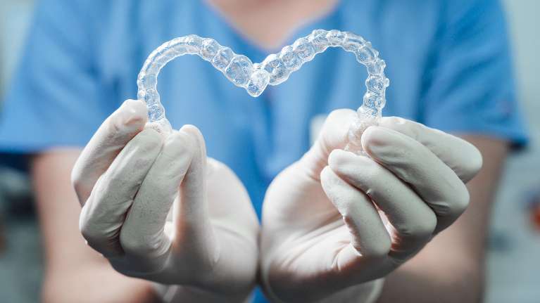 A dentist holding clear invisalign braces.
