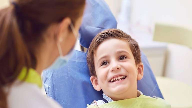 A young child smiling in the dentist's chair