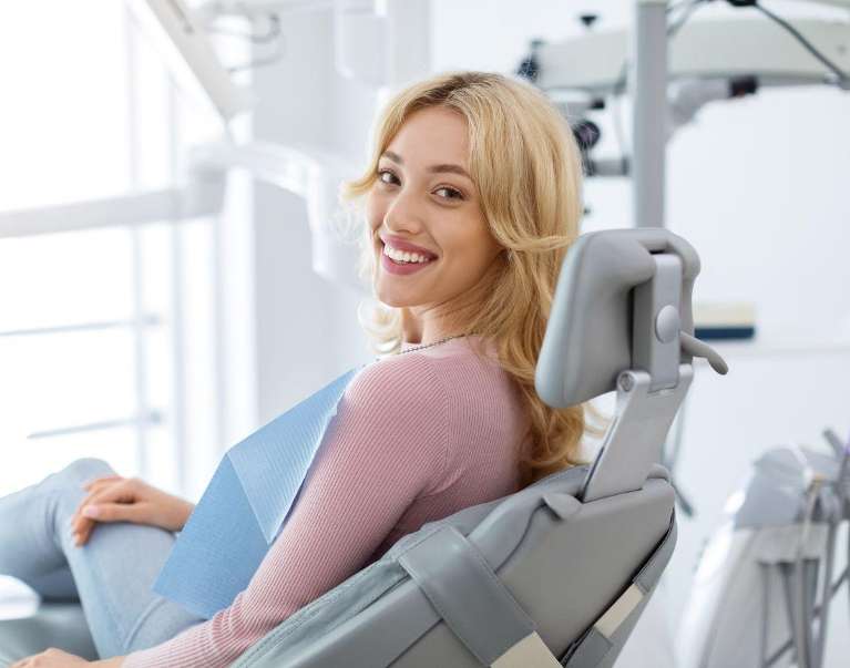 Woman blonde hair smiles on a dentist's chair, relieved covered Health Fund for Dental Care 