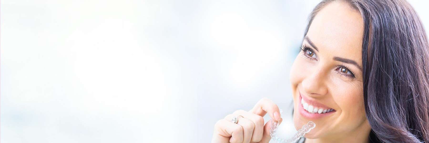 Woman putting in an Invisalign tray from Oasis Smiles Dental in Tamsworth, NSW